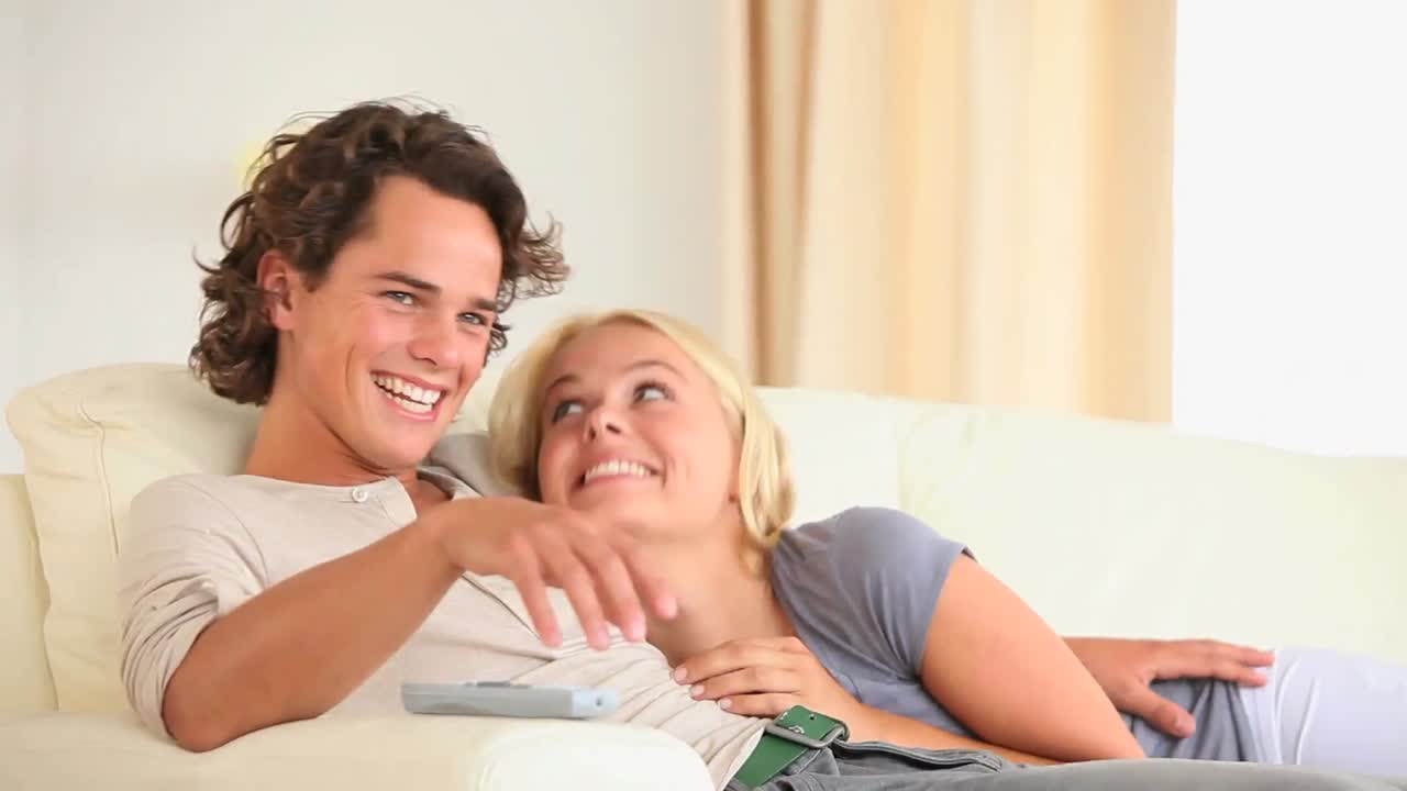 pareja feliz en un sofá viendo la televisión
