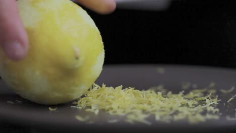 peel lemon little pieces left on the plate after been grated at the kitchen table while cooking tasty pie close-up detail shot