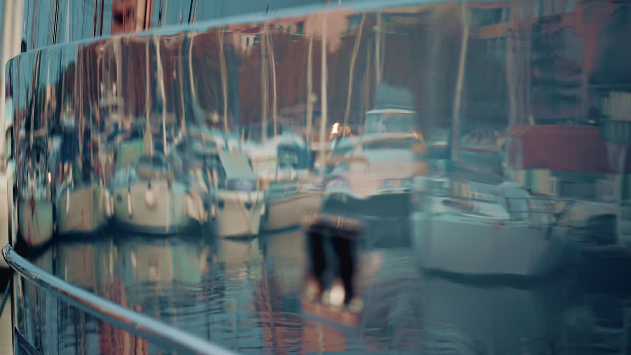 Reflections of marina boats distorted on the shiny surface of a yacht hull