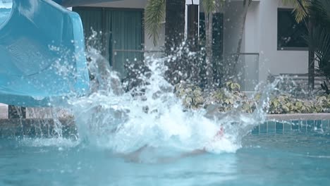 niño con las manos cruzadas monta tobogán acuático en la piscina cámara lenta