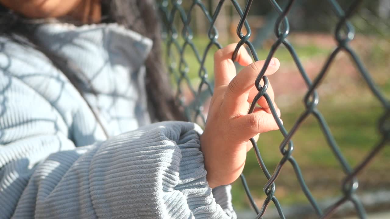 Child's hand on a metal fence