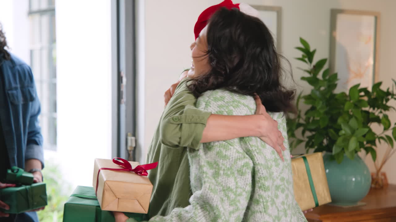 diverse friends hugging and exchanging gifts at home during Christmas celebration