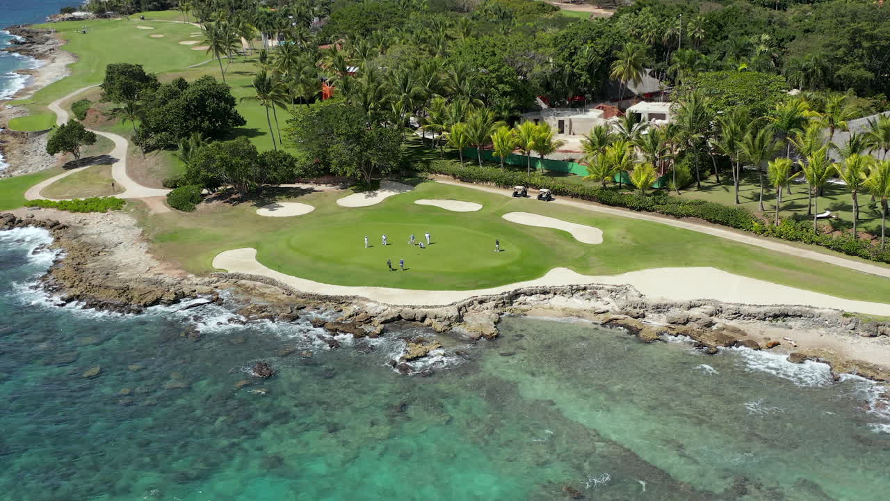 Aerial moving view of golfers on the green at a luxury ocean side golf course, La Romana, Dominican Republic
