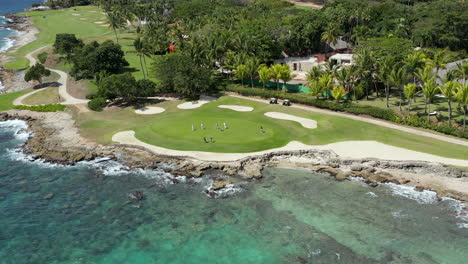 aerial moving view of golfers on the green at a luxury ocean side golf course, la romana, dominican republic