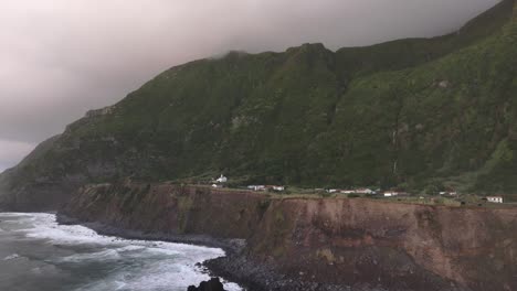 Rugged-coastline-at-Fajã-Grande-with-church-in-background,-aerial