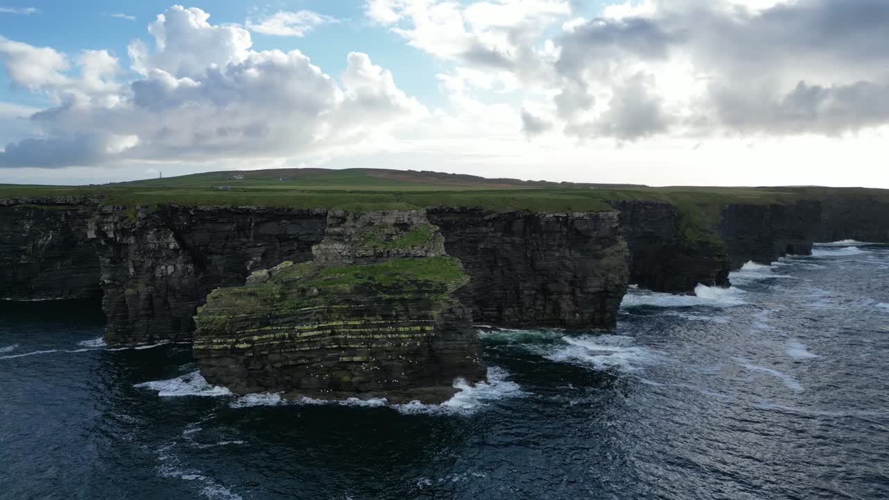 acantilados de kilkee en irlanda con olas que se estrellan contra costas rocosas bajo un cielo nublado, vista aérea