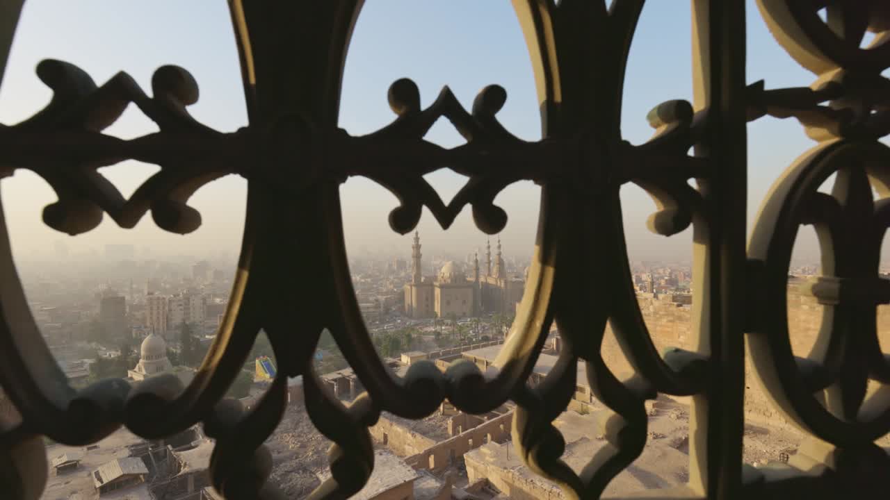 카이로의 도시와 술탄 하산의 모스크를 창문의 철 막대기를 통해 볼 수 있습니다.