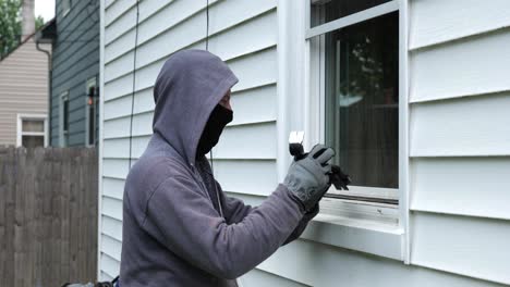 Einbrecher-öffnet-Ein-Fenster-Mit-Einem-Brecheisen-Und-Beginnt,-In-Ein-Haus-Zu-Klettern