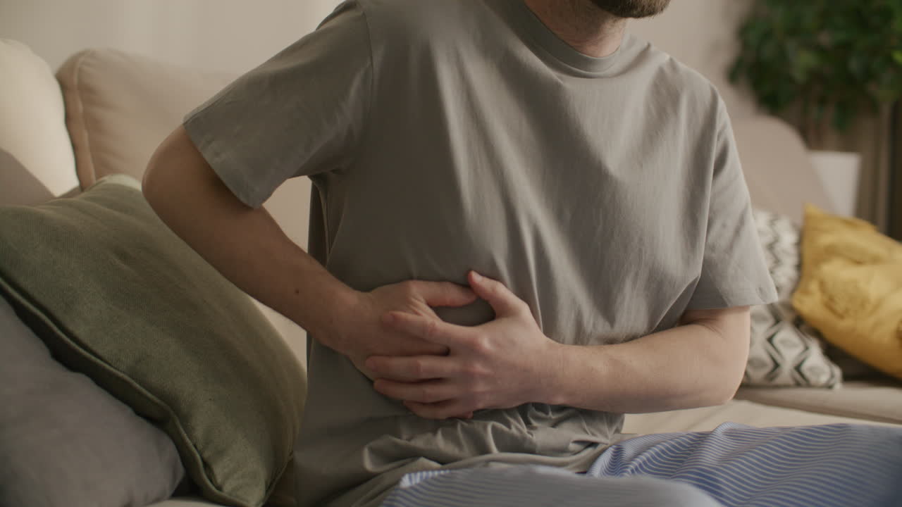 Man Suffering from Severe Abdominal Pain While Sitting on Couch