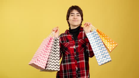 happy young woman with shopping bags on yellow background