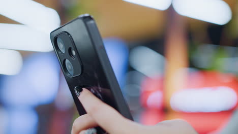 close-up of hand engaging with smartphone, showing vibrant blinking lights in blurred background, focus on phone interaction with colorful bokeh lighting