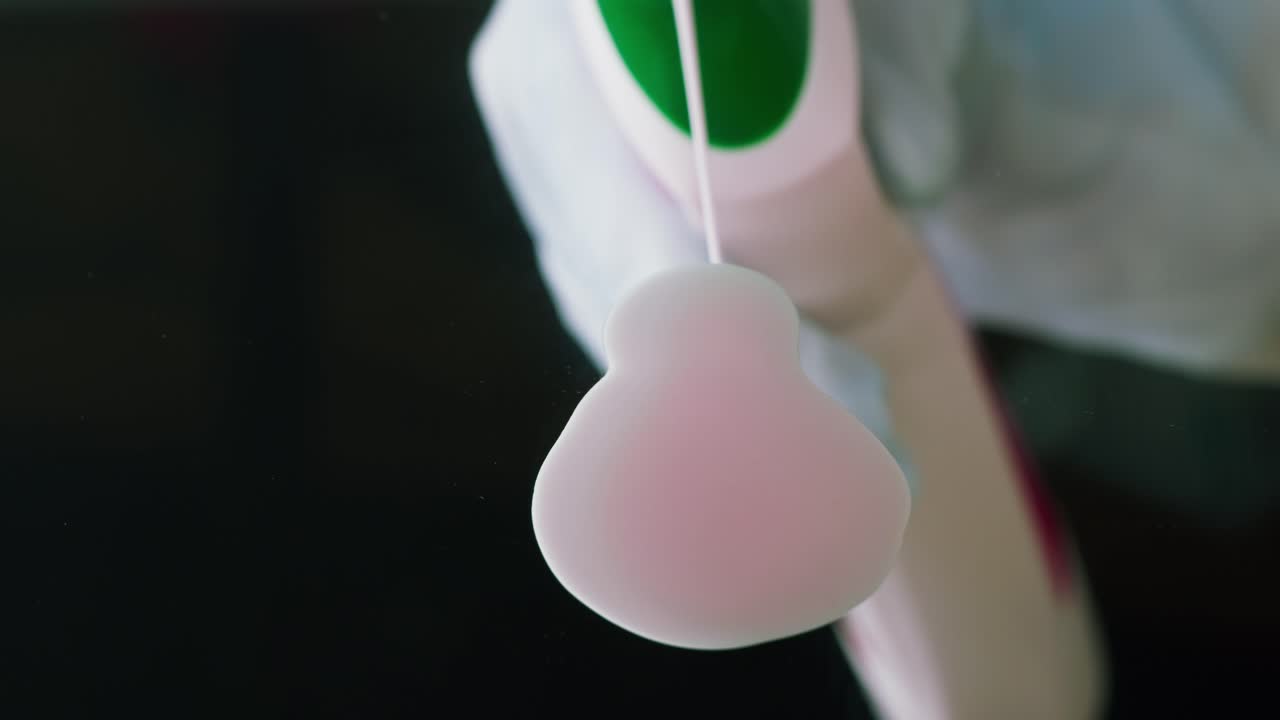 Primo piano di una mano con guanto che spruzza una soluzione detergente