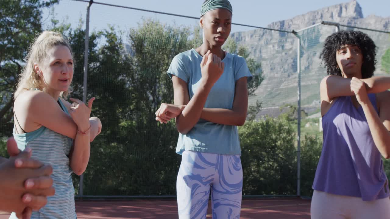 Happy diverse female basketball team training on sunny court, in slow motion