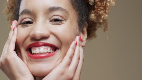 feliz mujer biracial con cabello oscuro y labios y uñas rojas en fondo beige, cámara lenta