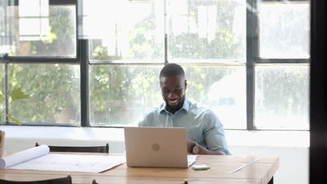 smiling businessman working on laptop at desk in bright office setting