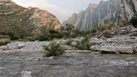 river flowing with mountains behind on a calm autumn afternoon with many rocks around