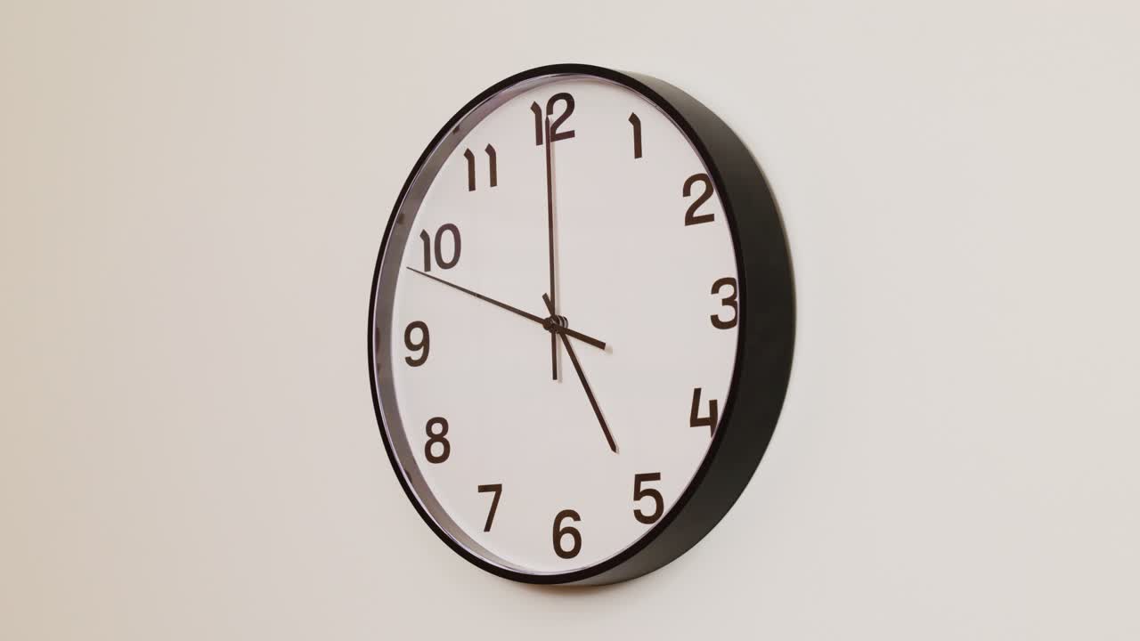 A close-up 4K shot of a black and white wall clock filling the frame, showing the time as 5:00.