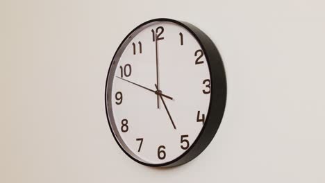 a close-up 4k shot of a black and white wall clock filling the frame, showing the time as 5:00.