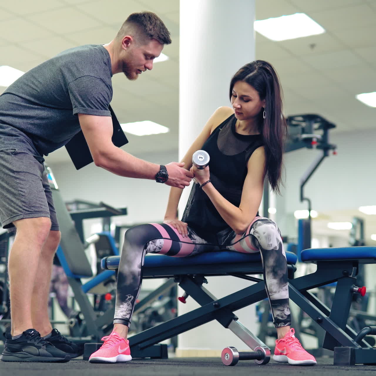 Young and beautiful woman working out with dumbbells in gym. Concept of a healthy lifestyle.
