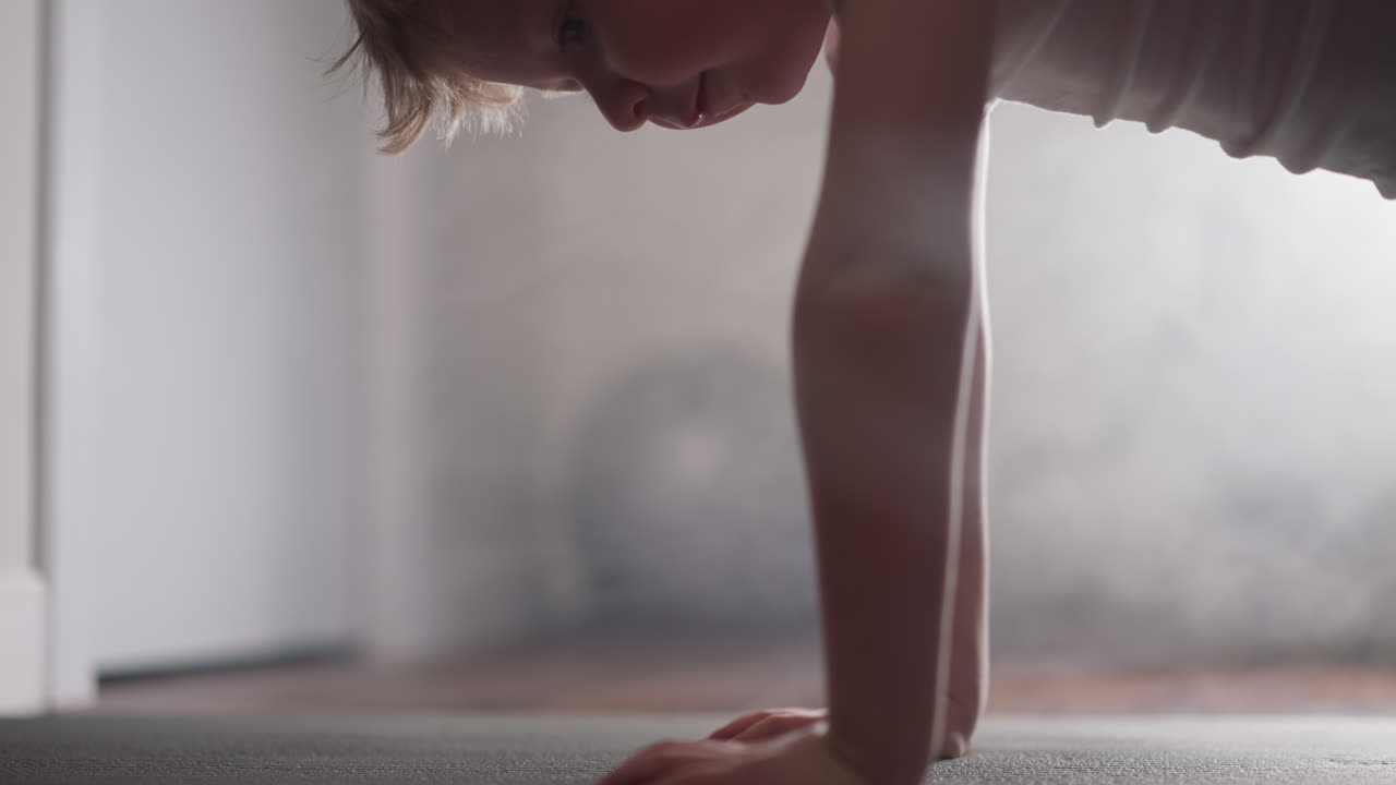 Un bambino piccolo fa flessioni sul pavimento in soggiorno, in primo piano.