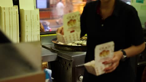 vendor prepares and packages pan-fried buns