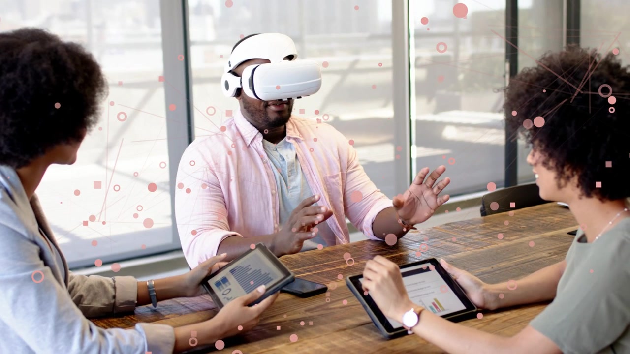 Man wearing VR headset leading tech demo, gesturing to virtual objects while team adjusting tablets