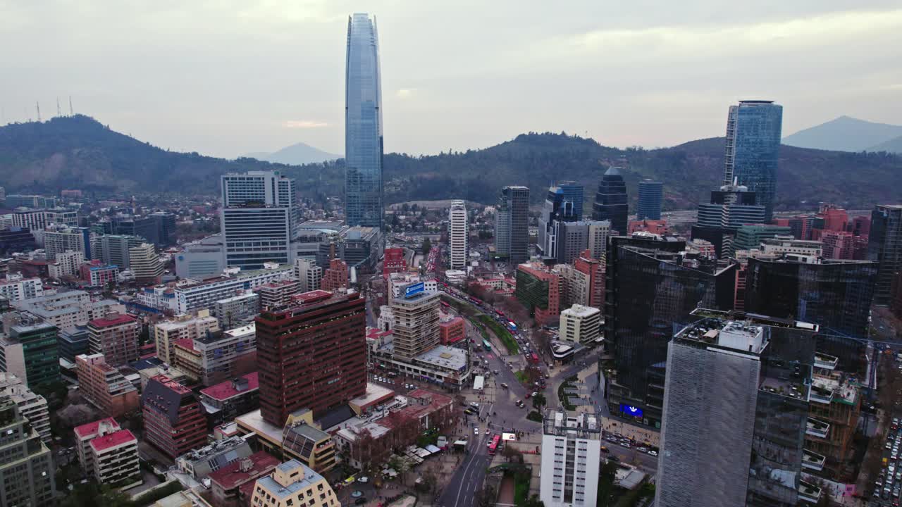 Dolly in establishing aerial view of the financial sector of Santiago Chile with the San Cristobal hill in the background on a cloudy day, Costanera tower
