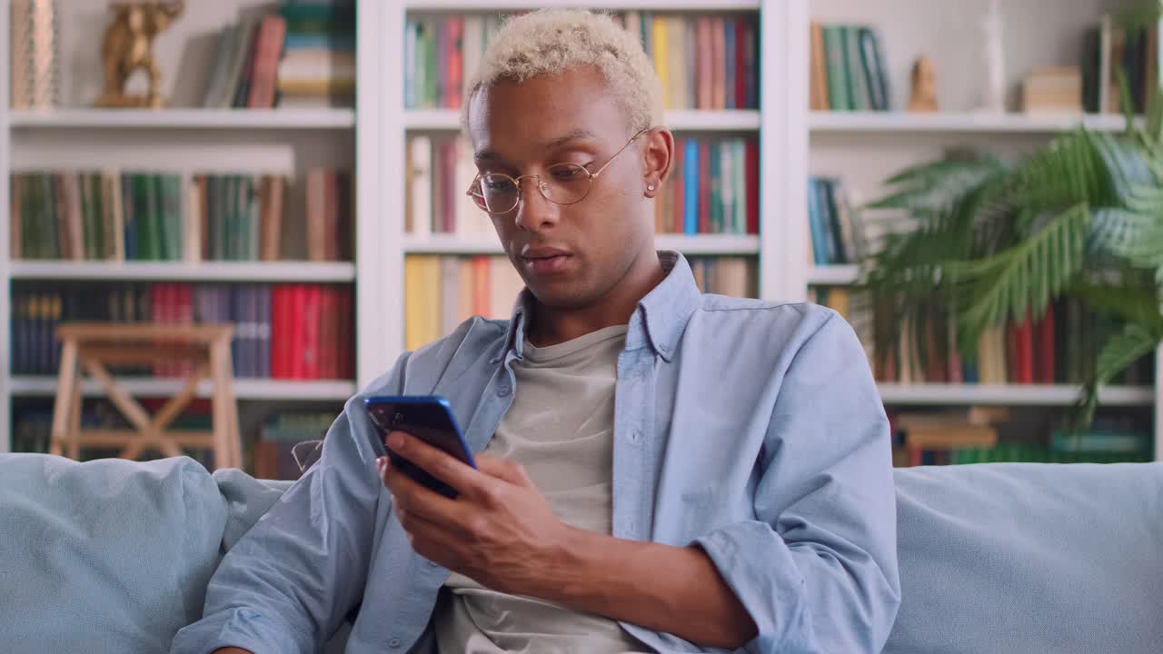 Young perplexed african american man learns bad news in phone reading email