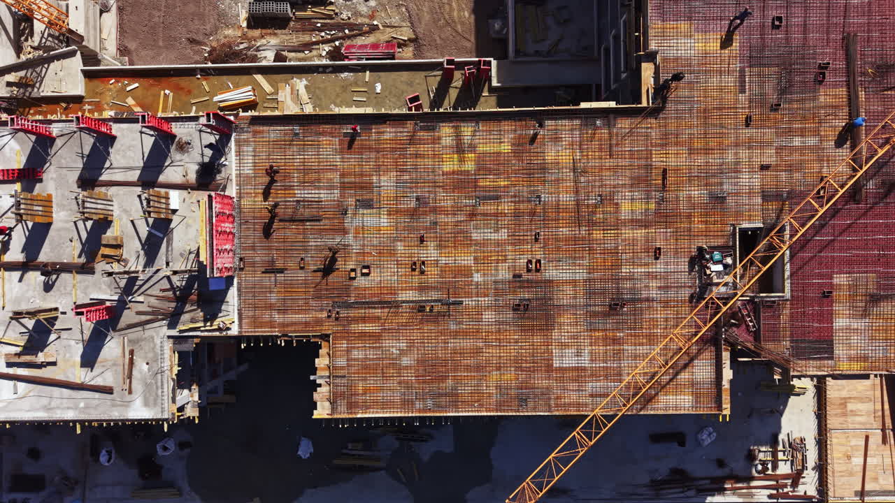 Construction work is underway on a large foundation at a building site in an urban area during the middle of the day