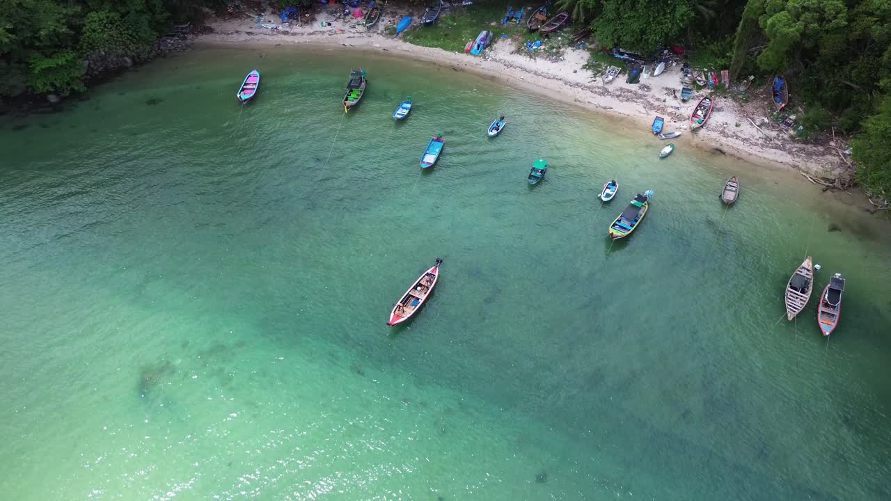Cảnh quay từ flycam nhìn từ trên cao thuyền đuôi dài truyền thống neo đậu trên mặt nước trong xanh ngọc bích trong vắt cạnh bãi biển cát nhỏ ở Patong Phuket Thái Lan. Điểm đến du lịch nhiệt đới
