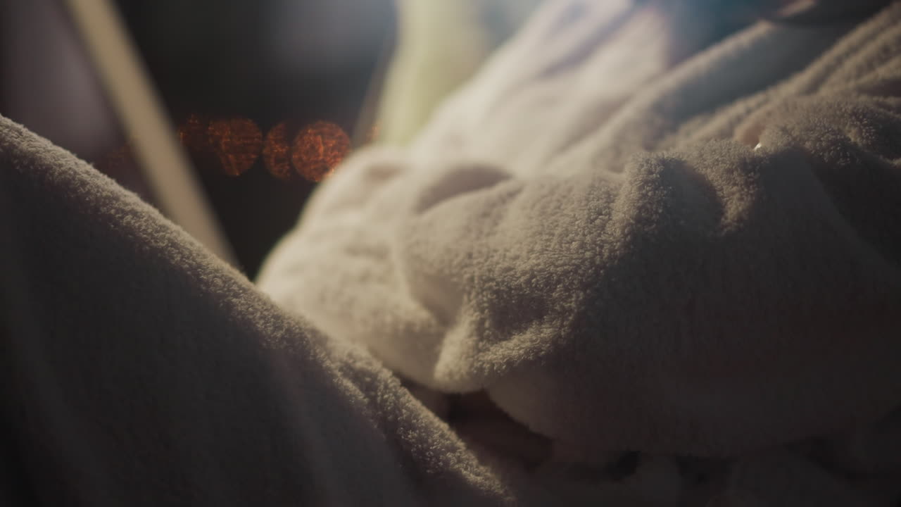 팔을 은 여자가 해가 지는 모습을 볼 수 있는 발코니에 앉아 있다. 털털한 색 욕조를 입은 여자가 편안한 의자에서 넓은 파노라마 창문을 바라보고 있다.