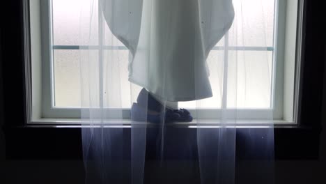 신부의 웨딩 베일과 큰 창턱에 놓인 그녀의 신발 위에 드리워진 드레스의 느린 슬라이더