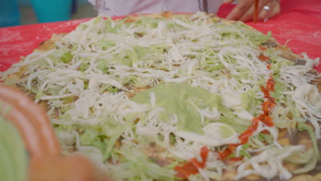 preparing traditional food tlayuda with traditional oaxaca cheese quesillo, guacamole, salsa