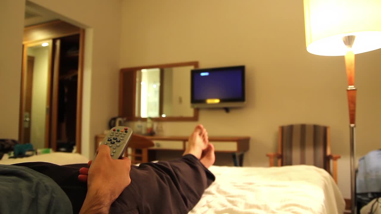 Giovane uomo che guarda la TV nella camera d'hotel 1