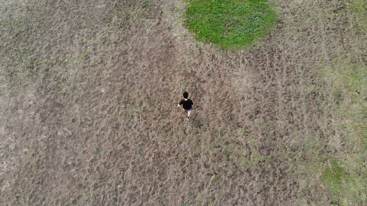 공중 뷰: 사람이 리모컨을 내려놓고 드론을 만들었고, 공허한 땅에서 달리는 동안 따라다다.