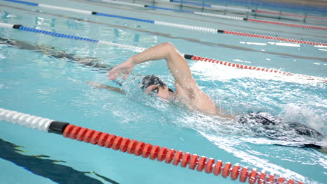 swimming in pool, male athlete performing freestyle stroke during swim practice