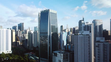 Aerial-view-circling-in-front-of-the-Makati-city-skyline,-in-sunny-Manila,-Philippines