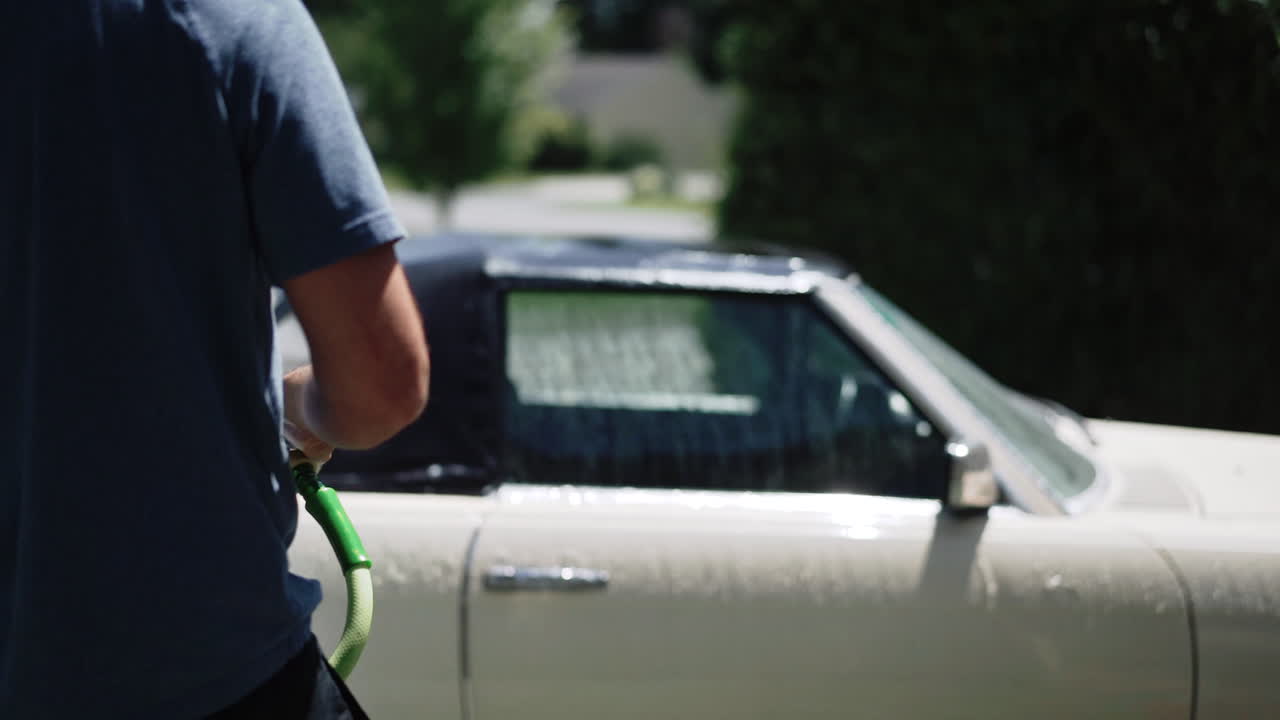 Man Washing a Classic Car with a Hose