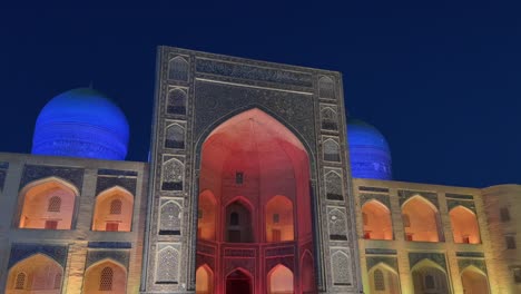 Toma-Orbital-De-4k-Que-Muestra-La-Madrasa-Mir-i-arab-Por-La-Noche-En-El-Casco-Antiguo-De-Bukhara,-Uzbekistán