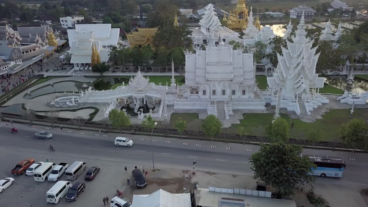 Thailand,Chaing Rai,White Temple, Drone footage of the white temple's from a horizontal angle,footage turns around the temple,traffic and cars around the temple,people waiting at the entrance,walking.