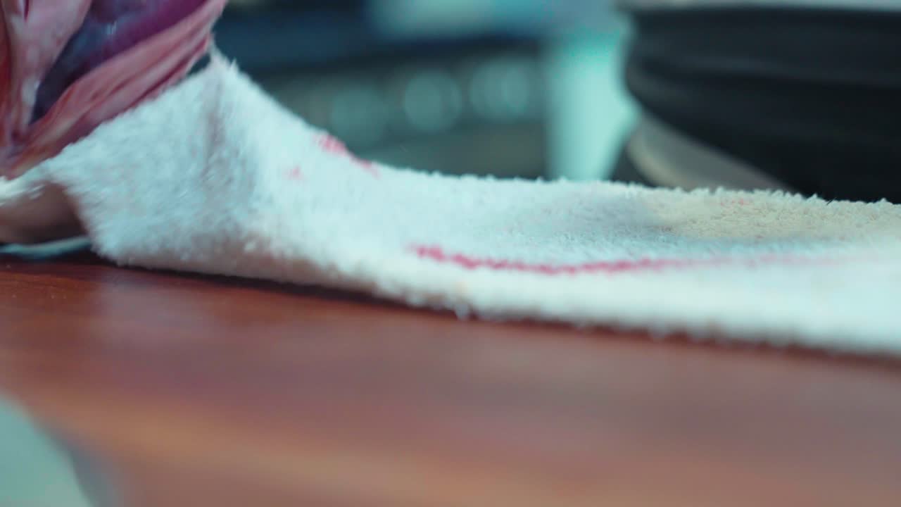 A static shot captures fish being picked up as a towel is set for culinary prep, emphasizing precise handling and kitchen efficiency. Ideal for food and restaurant content.