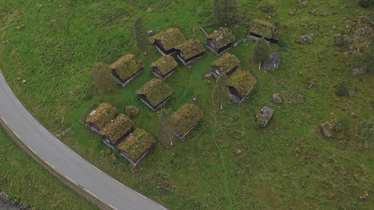 Traditionelle hytter nær turkis sø og bjergtoppe i Norge.