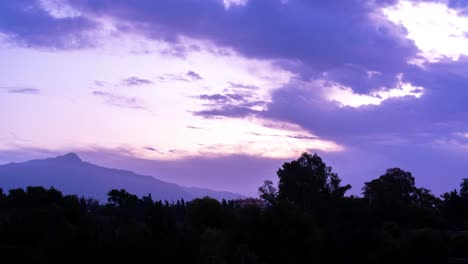 4k cloudy sunrise, blue-purple hue clouds, shot in marbella, malaga, with a big mountain in background and tree silhouettes in the foreground