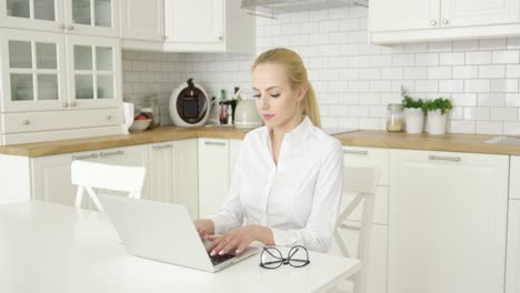 Young-woman-using-laptop-at-kitchen