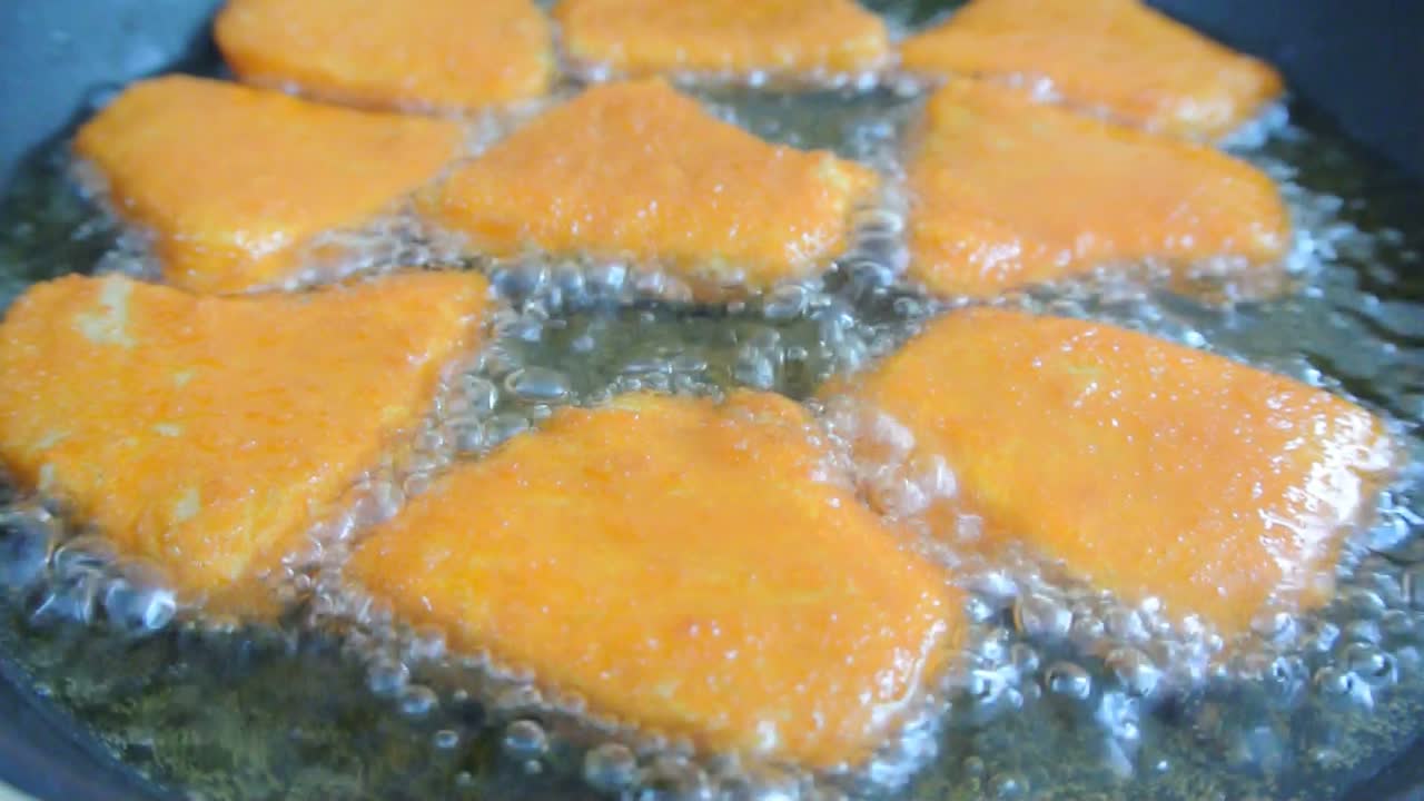 Chicken nuggets are fried using cooking oil in a pan