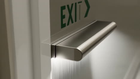 close-up of an emergency exit door with panic bar and green exit sign