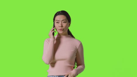 녹색 스크린 에 대해 휴대 전화 로 이야기 하는 여자 의 스튜디오