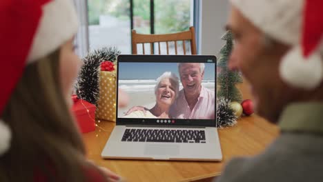 Caucasian-granddaughter-and-grandfather-on-video-call-with-senior-couple-at-christmas-time