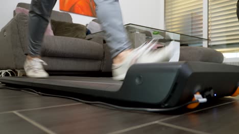 low angle shot of male person walking on treadmill at home during quarantine time