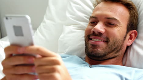 un hombre está enviando mensajes de texto en su cama